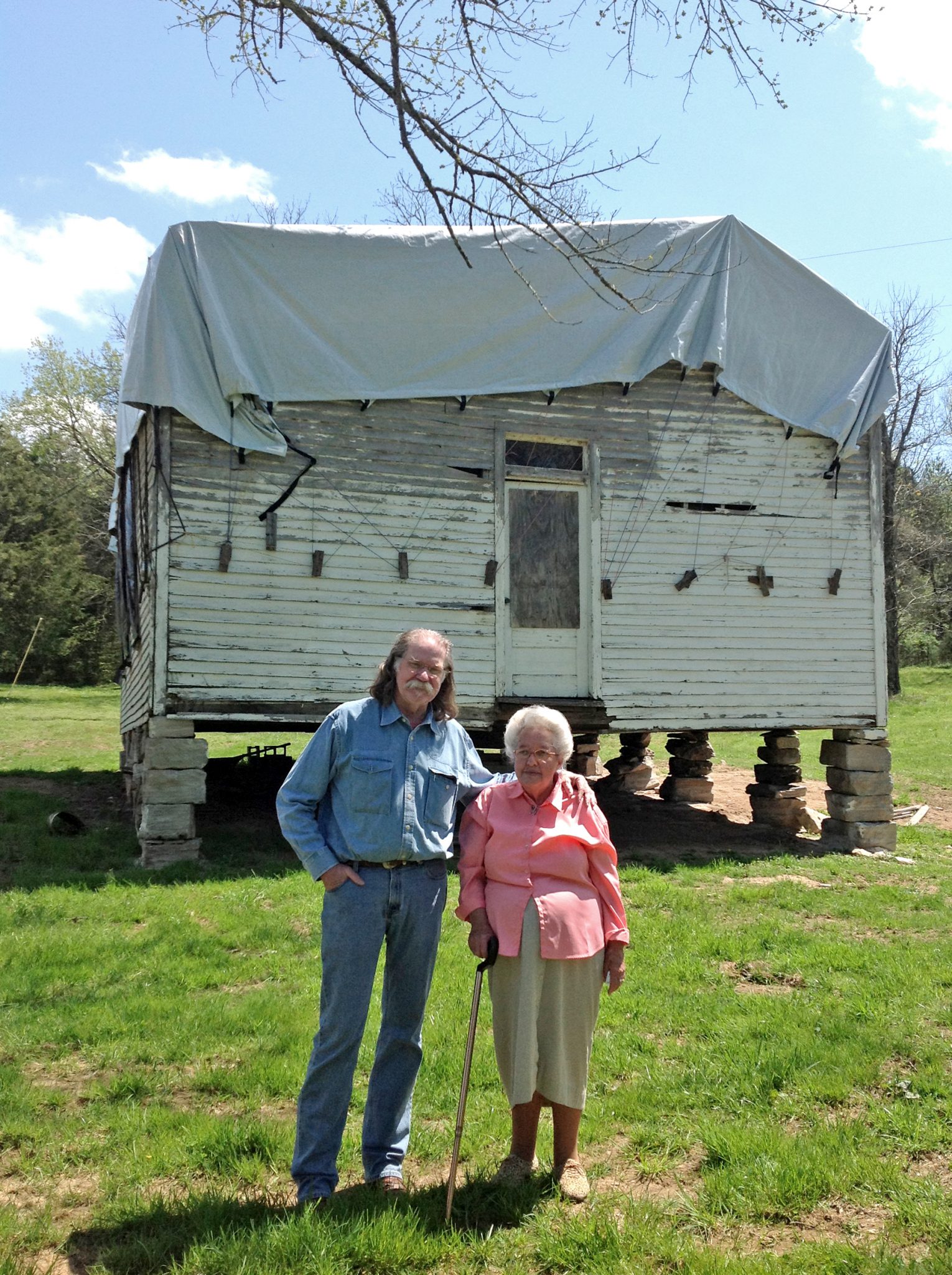 Colonel standing with Clara Graves in front of un-restored one-room schoolhouse