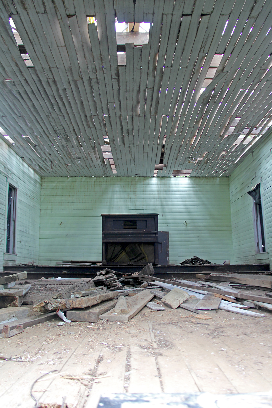 Inside of unfinished one-room schoolhouse with loose boards scattered on the floor