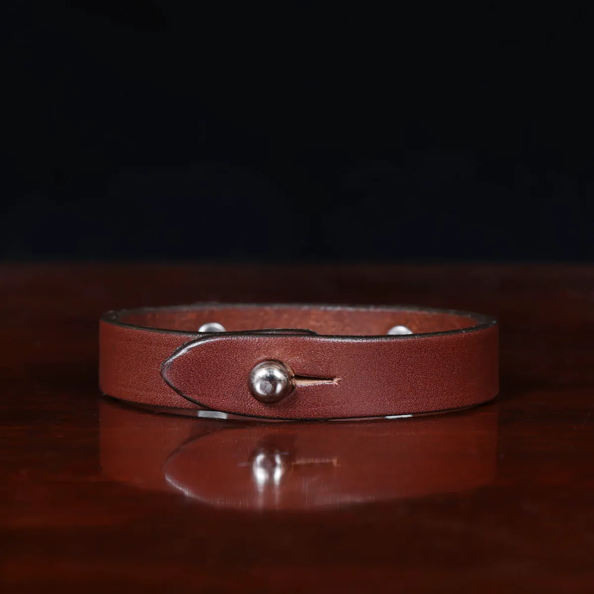 camp bracelet in vintage brown leather on a wooden table and a dark background - nickel - back view