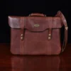 no 16 brown vintage leather document bag with strap on a wooden table with a dark background - front view