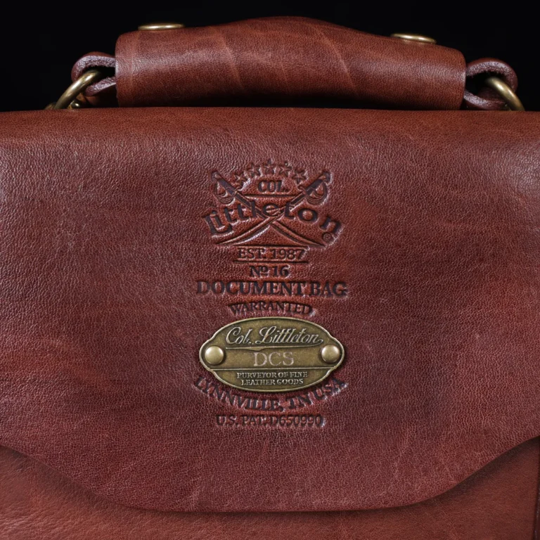 no 16 brown vintage leather document bag with strap on a wooden table with a dark background - view of logo and personalization