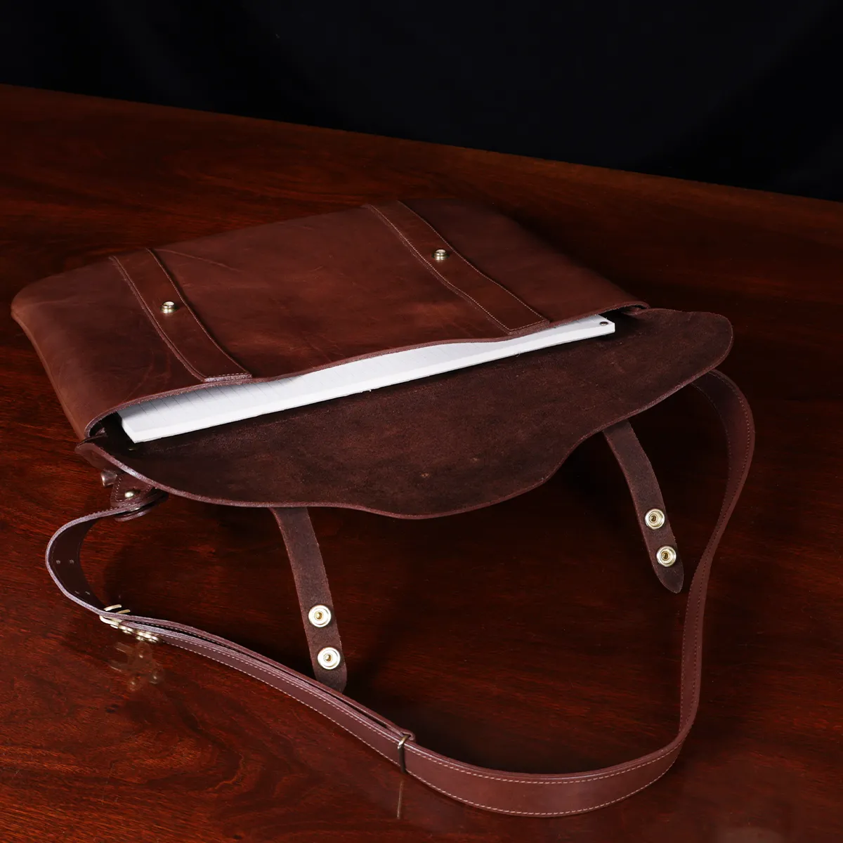 no 16 brown vintage leather document bag with strap on a wooden table with a dark background - open view
