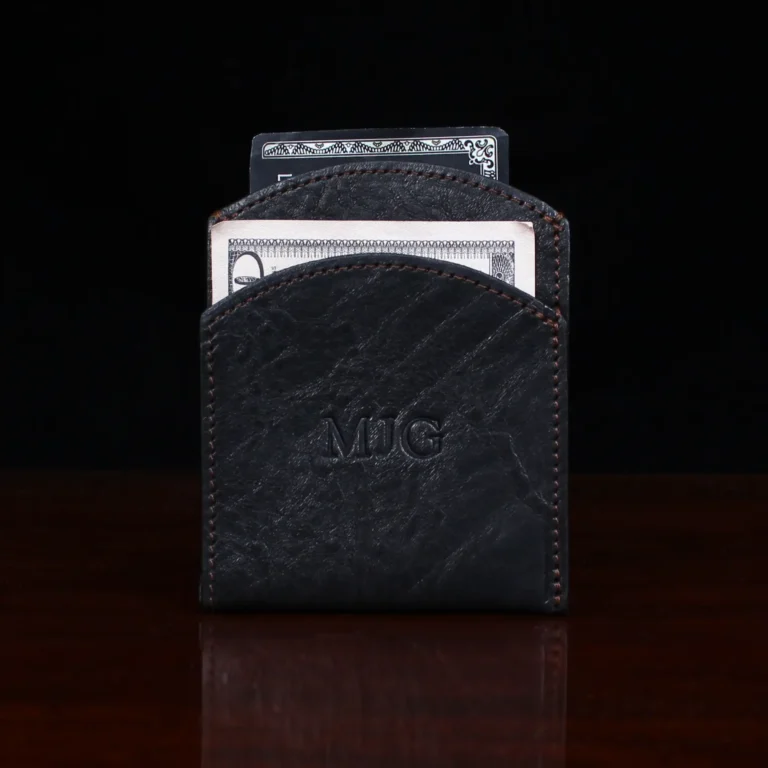 black leather front pocket wallet on wood shelf with money