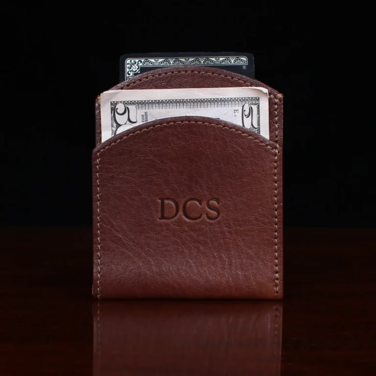 brown leather front pocket wallet on wood shelf with money