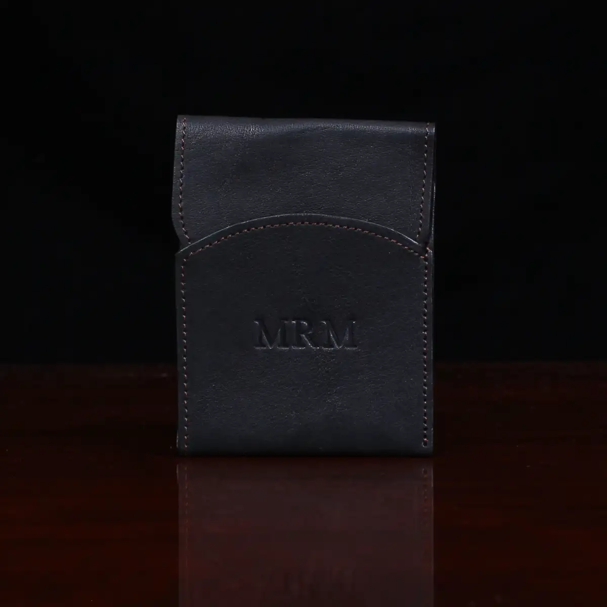 black leather front pocket wallet with flap on wood table