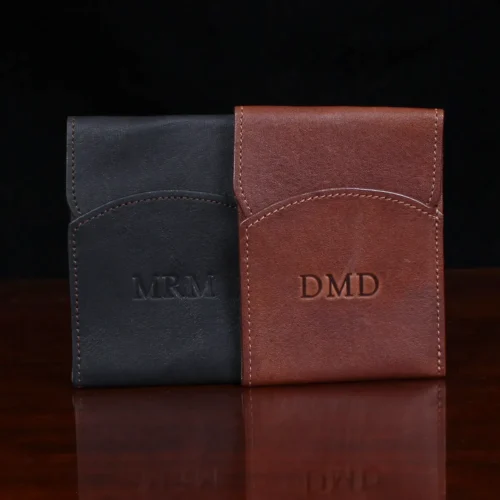 black and brown leather front pocket wallet with flap on wood table