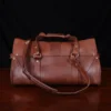 leather travel bag - back view- on a wooden table with a dark background