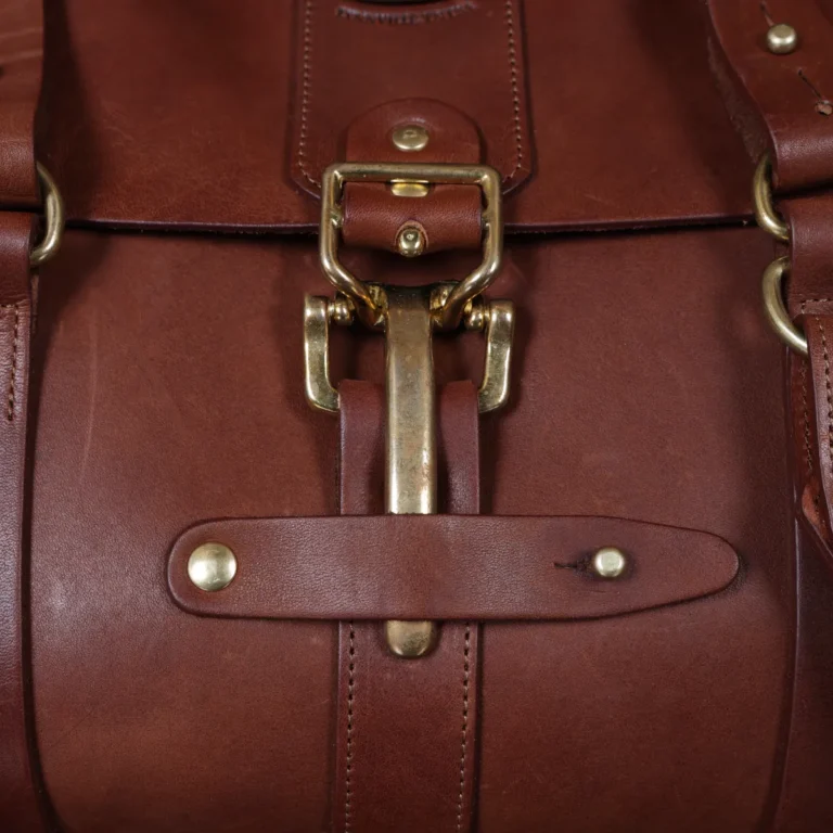 leather travel bag - buckle view- on a wooden table with a dark background