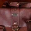 leather travel bag - personalization view- on a wooden table with a dark background