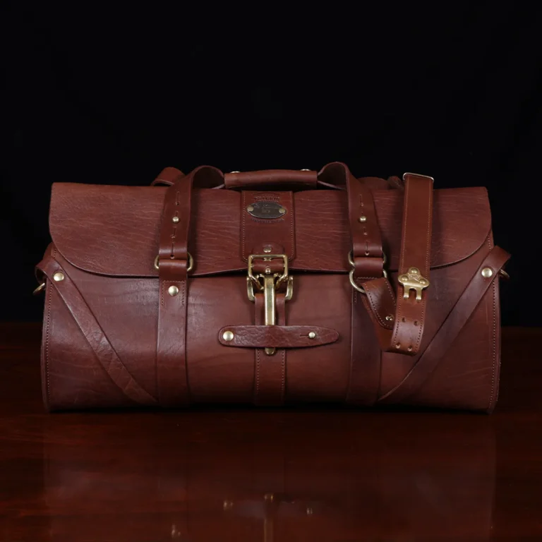leather travel bag - front view- on a wooden table with a dark background