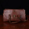 leather travel bag - open front view- on a wooden table with a dark background