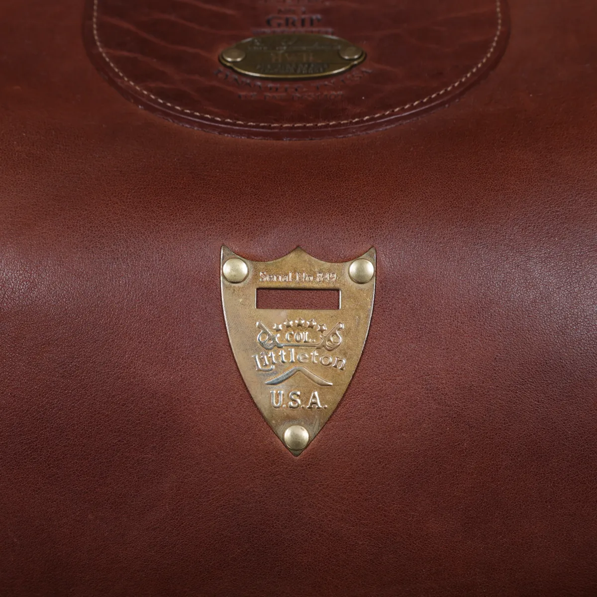 Vintage-style dark brown No. 3 Grip Bag on wooden table with a dark background - view of pommel shield