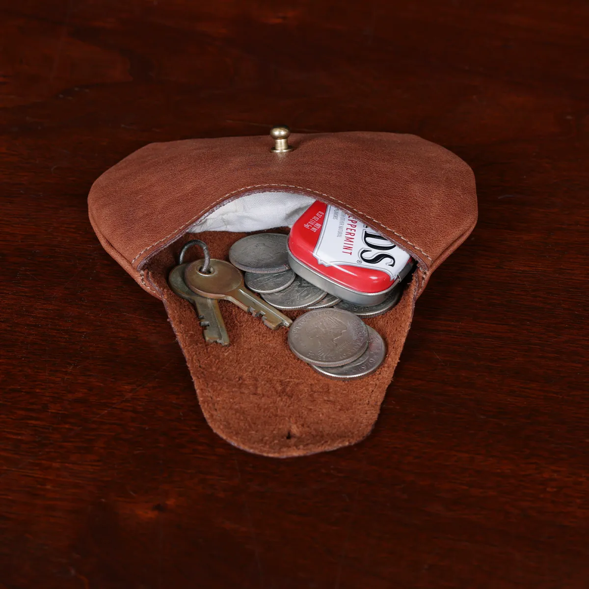 no1 leather vintage brown pouch open on a wooden table with coins, keys, and mints spilling out