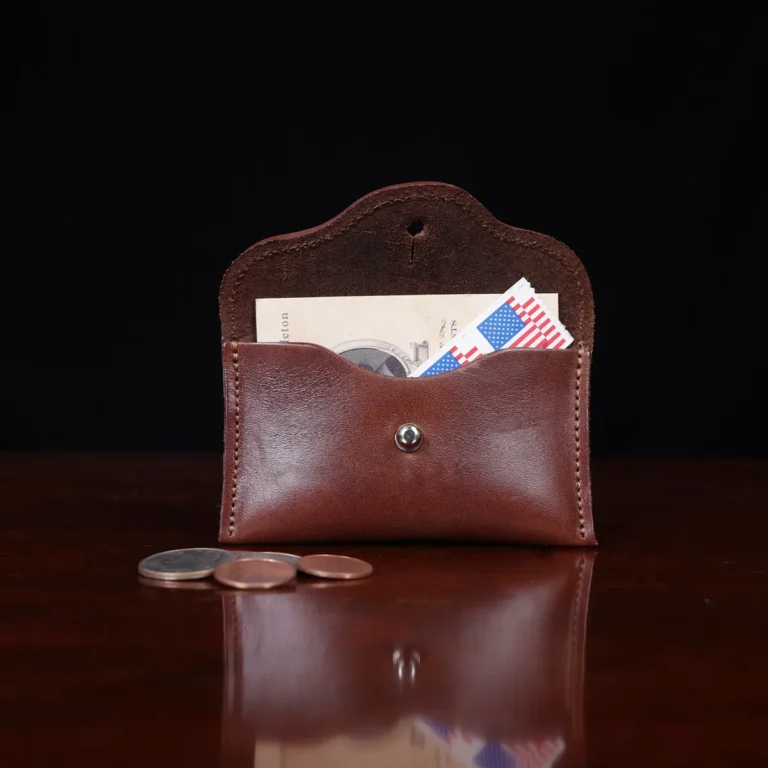 no15 vintage brown american leather pouch on a wooden table with a dark background with stamps, coins and business card