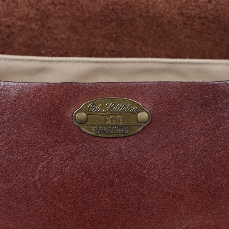 No. 1 Saddlebag Briefcase on a wooden table with a dark background - front view of initial plate