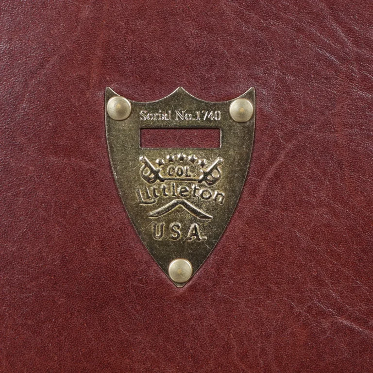 No. 1 Saddlebag Briefcase on a wooden table with a dark background - front view of pommel shield