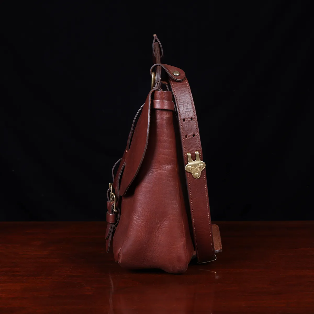 No. 1 Saddlebag Briefcase on a wooden table with a dark background - left side view