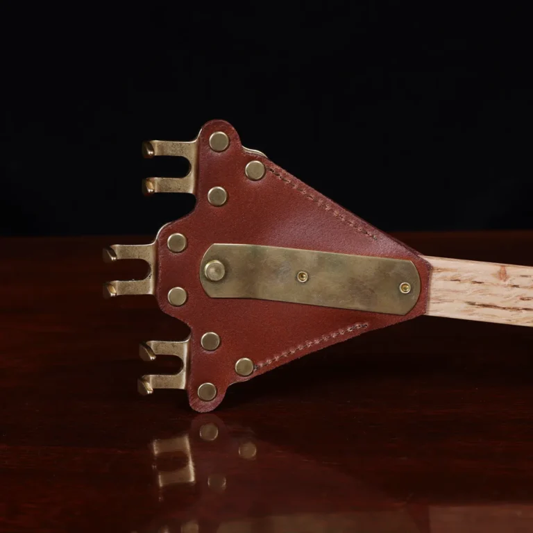 back scratcher made of solid brass on a wooden table with a dark background - back view