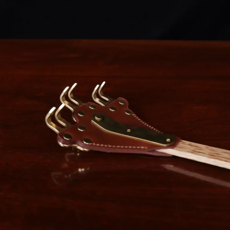 back scratcher made of solid brass on a wooden table with a dark background - scratchers