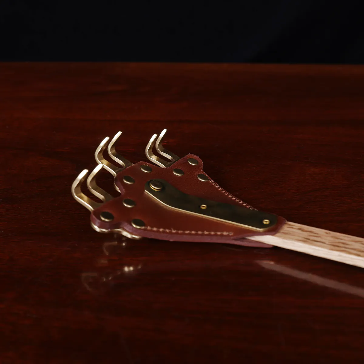 back scratcher made of solid brass on a wooden table with a dark background - scratchers