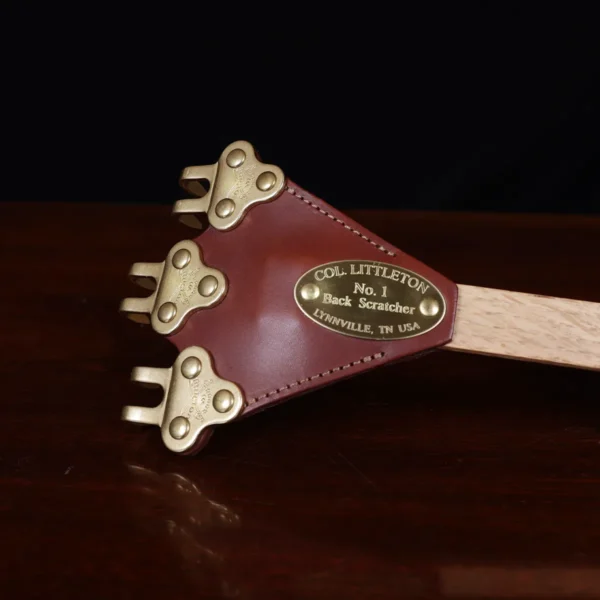 back scratcher made of solid brass on a wooden table with a dark background