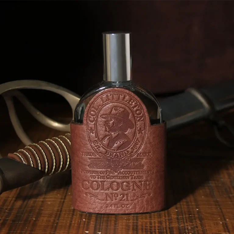 Cologne bottle sitting on wooden table with vintage sword handle behind it.