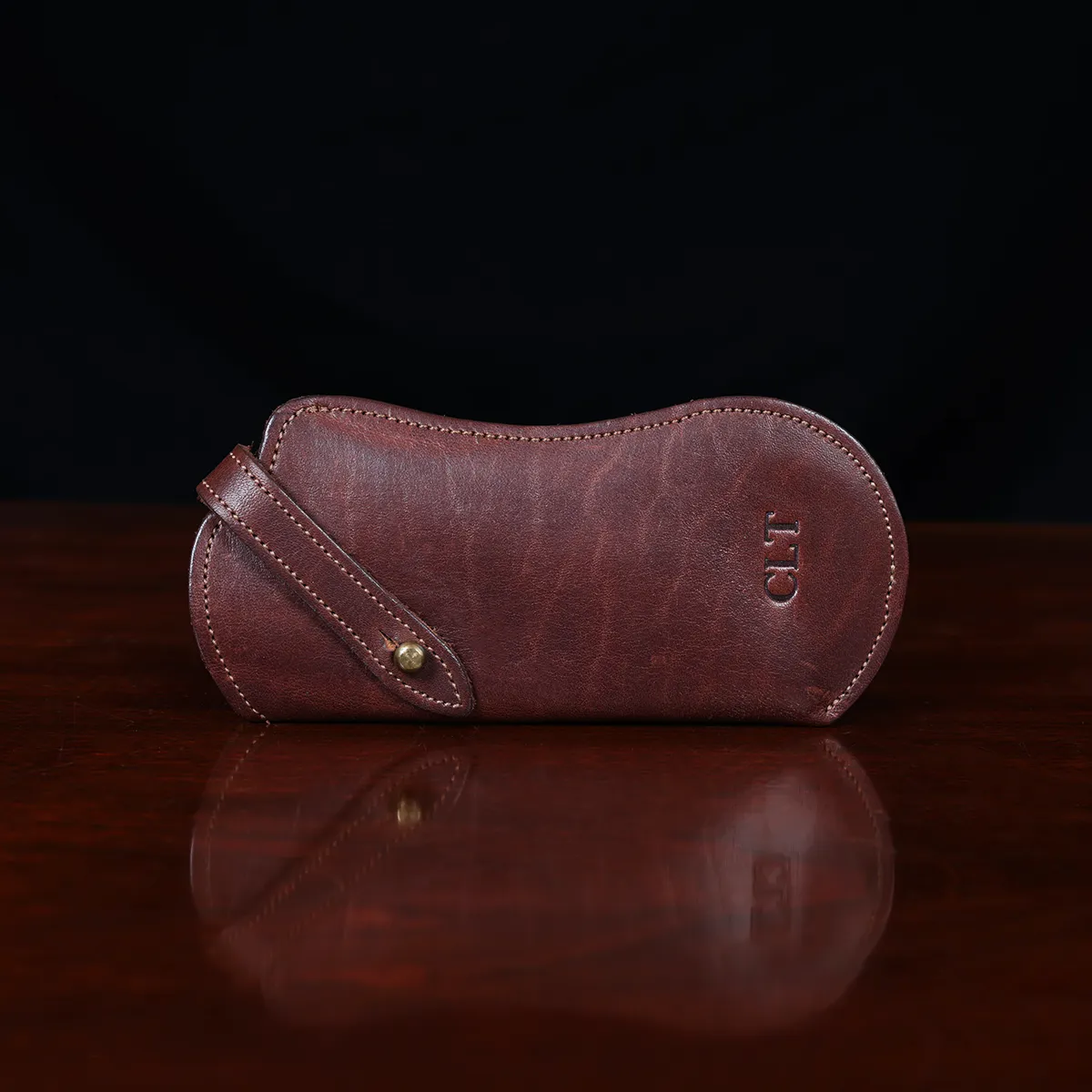Brown leather No. 2 Eyeglass Case on top of a wooden table with a dark background
