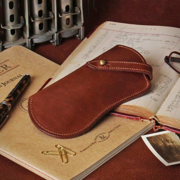 Brown leather No. 2 Eyeglass Case on top of an old book and paper journal