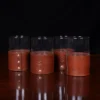 set of four leather veranda glass sleeves and glasses on wooden table with dark background
