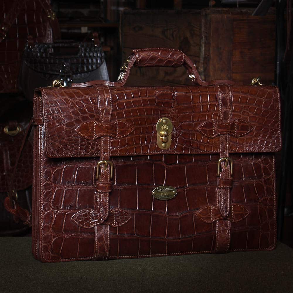 No. 1943 Navigator Briefcase in Vintage Brown American Alligator on green fabric with dramatic dark lighting