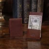 no 102 vintage brown billfold with personalization stamp - showing one open with cash and one closed with personalization on a wood table with books