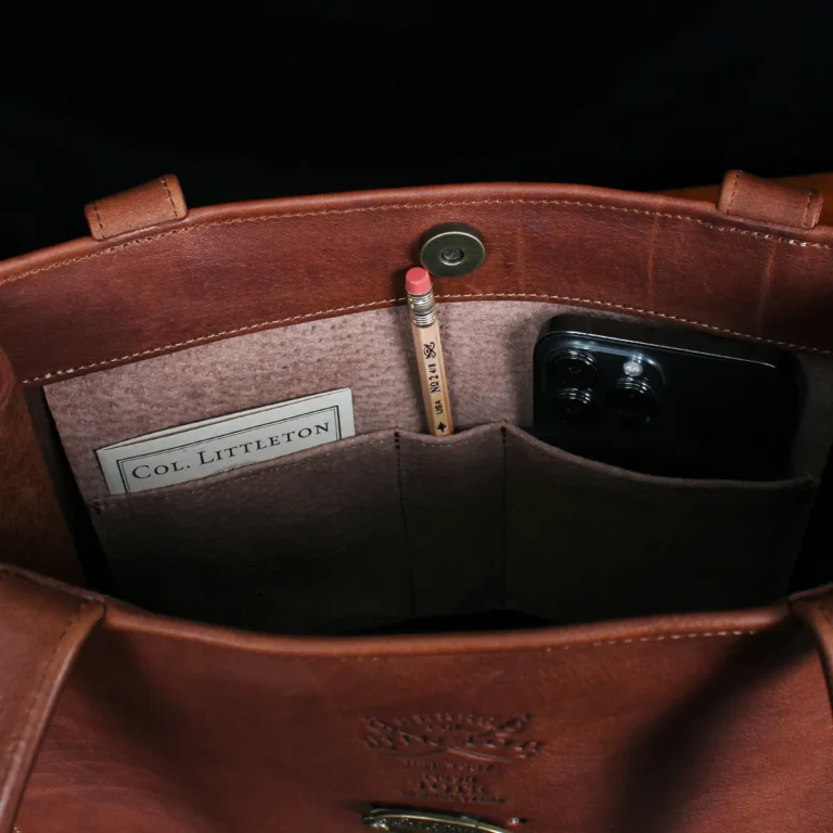 No. 9B Leather Tote in Vintage Brown - inside view with phone, pencil, and card - on wood table with dark background
