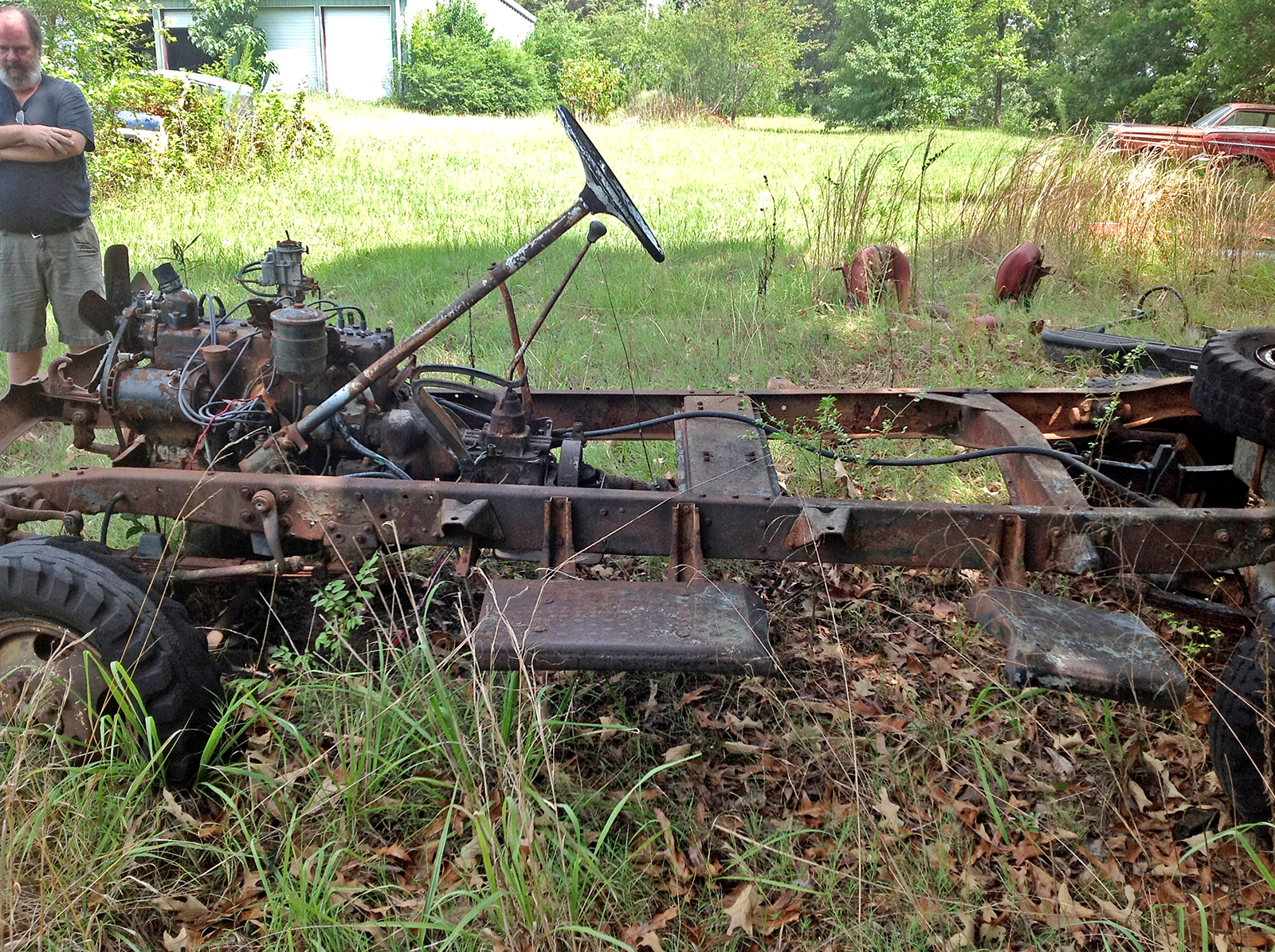 Side view of a very rusted and overgrown 1941 Army Command Car.