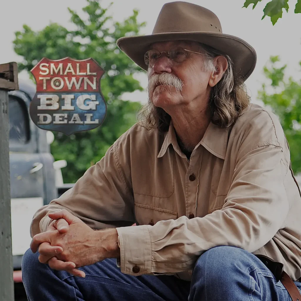 colonel sitting with hat on featuring small town big deal logo