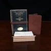 A pocket journal sitting next to the archive box, 3 journals, 3 brass paperclips, and 50 notecards.