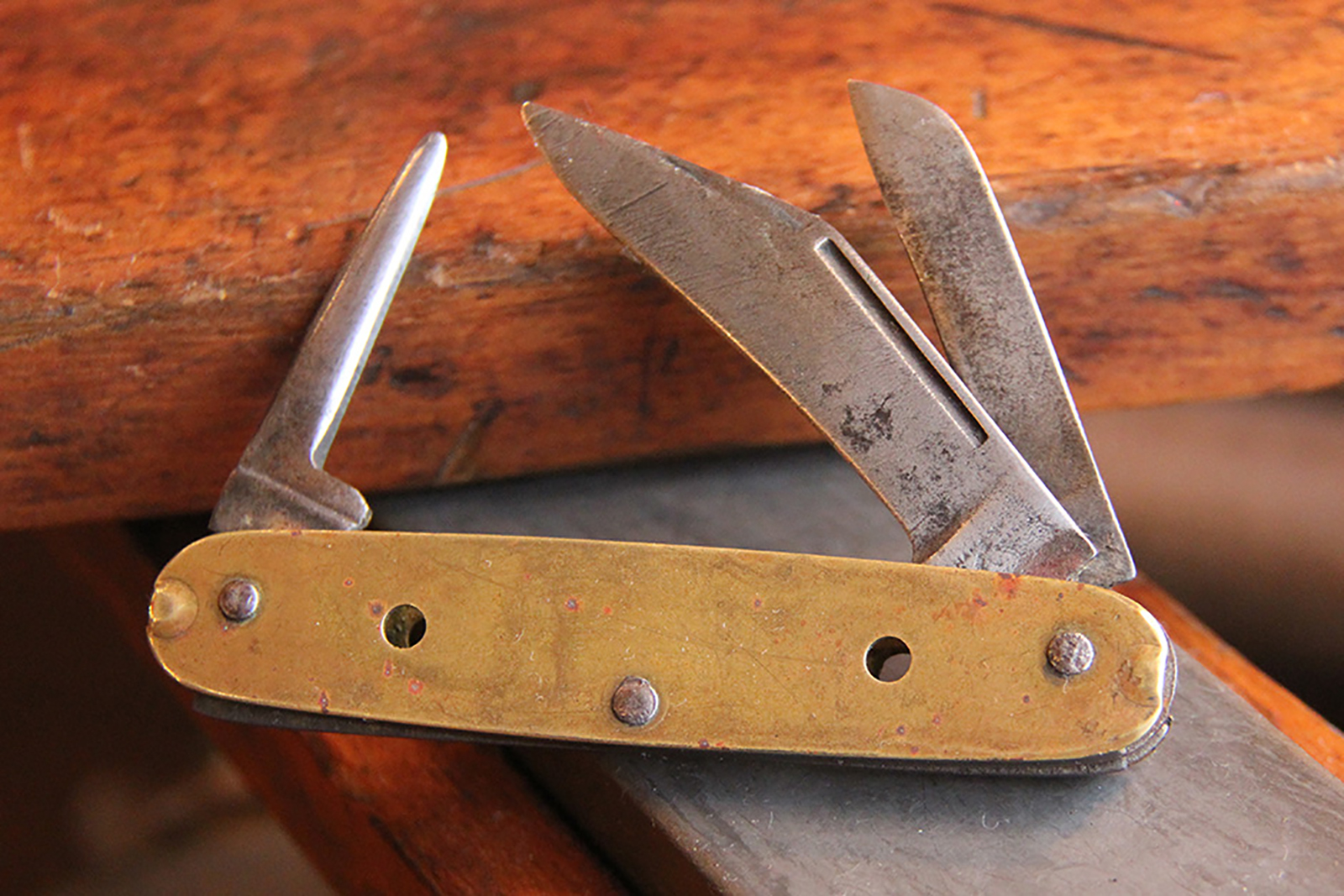 Colonel's Grandfather's brass whittling knife, open with worn blades showing.