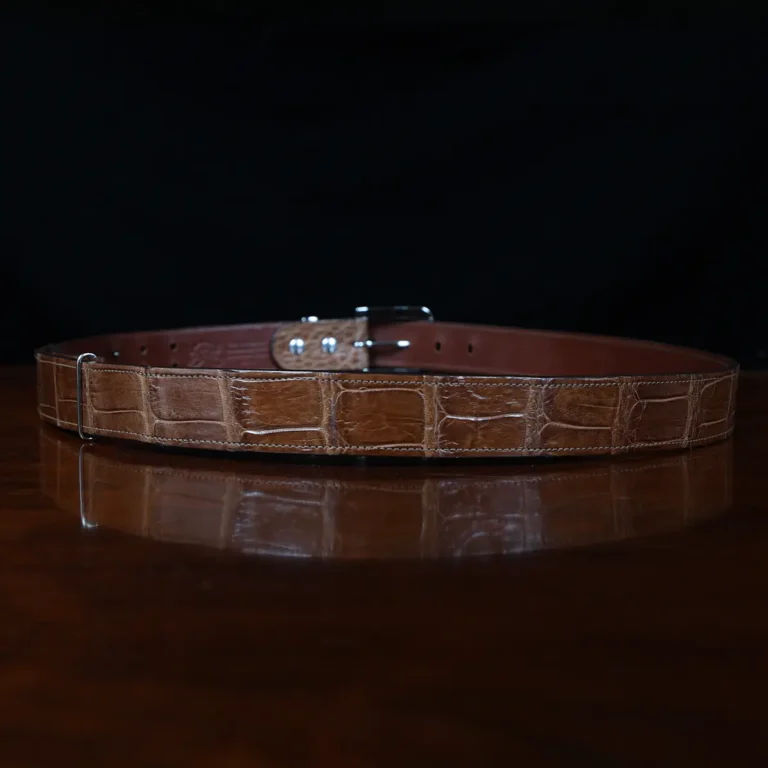 An American Alligator Belt with Nickel hardware showing the back view on a wooden table with black background - id 001