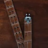 An American Alligator Belt with Nickel hardware showing the open hook view on a wooden table with black background - id 001