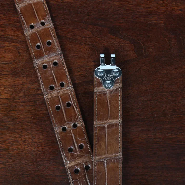 An American Alligator Belt with Nickel hardware showing the open hook view on a wooden table with black background - id 001