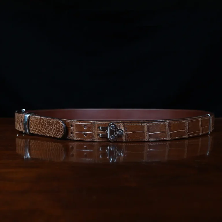 An American Alligator Belt with Nickel hardware showing the side view on a wooden table with black background - id 001