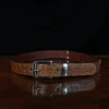 An American Alligator Belt with Nickel hardware showing the front view on a wooden table with black background - id 002