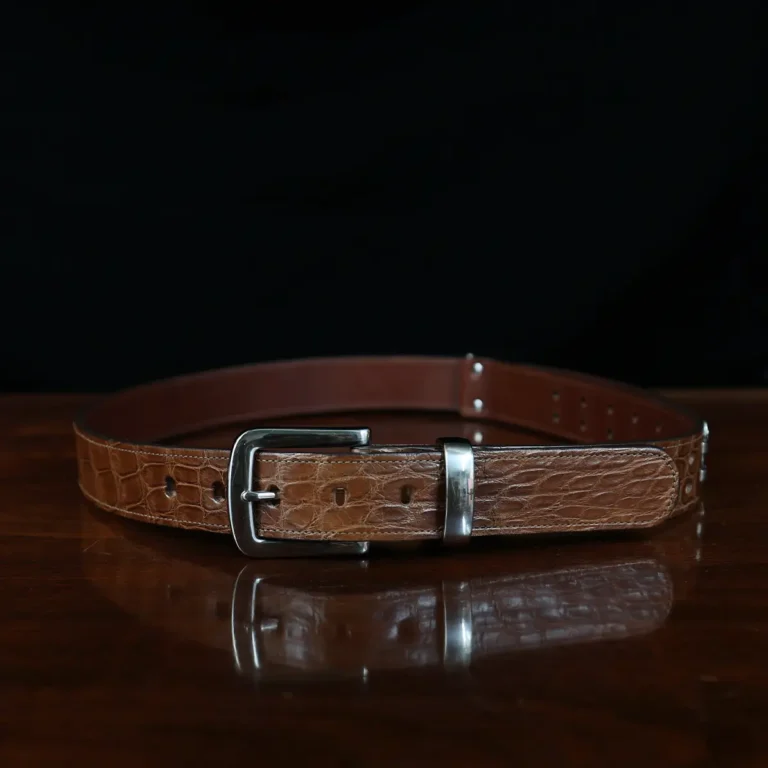 An American Alligator Belt with Nickel hardware showing the front view on a wooden table with black background - id 002