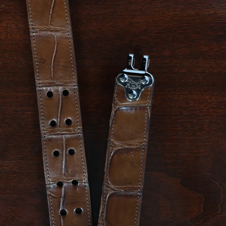 An American Alligator Belt with Nickel hardware showing the open hook view on a wooden table with black background - id 001
