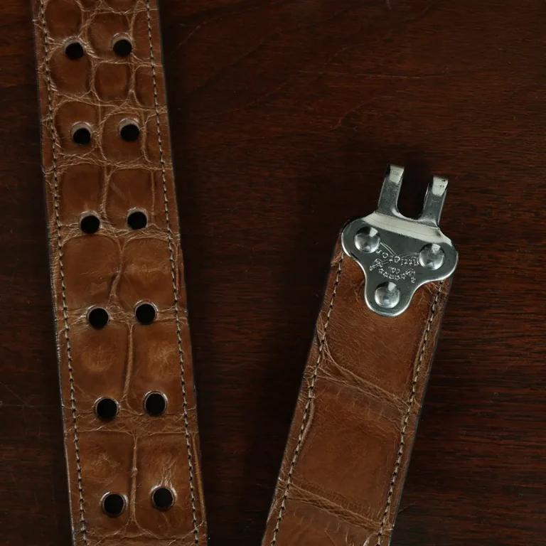 An American Alligator Belt with Nickel hardware showing the hook on a wooden table with black background - id 002