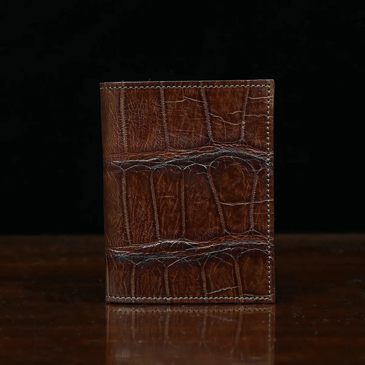 View larger image of No. 2 card wallet in Vintage Brown American Alligator - ID 001 - front view on a wood table and dark background