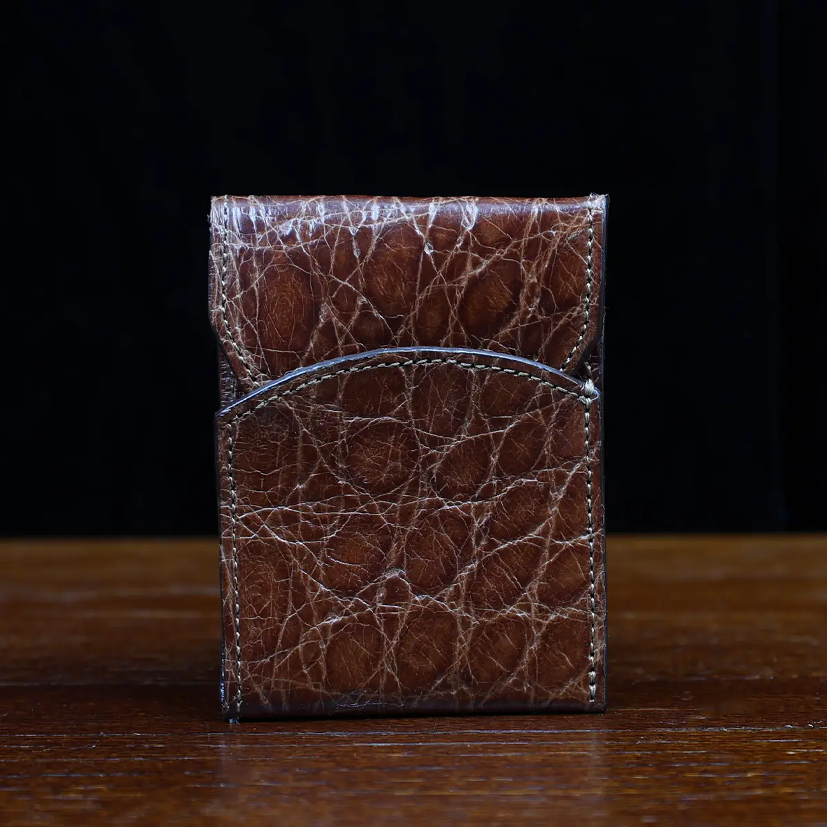 View larger image of Front pocket wallet with flap in brown American Alligator - front view - 001 - on wood table with a dark background
