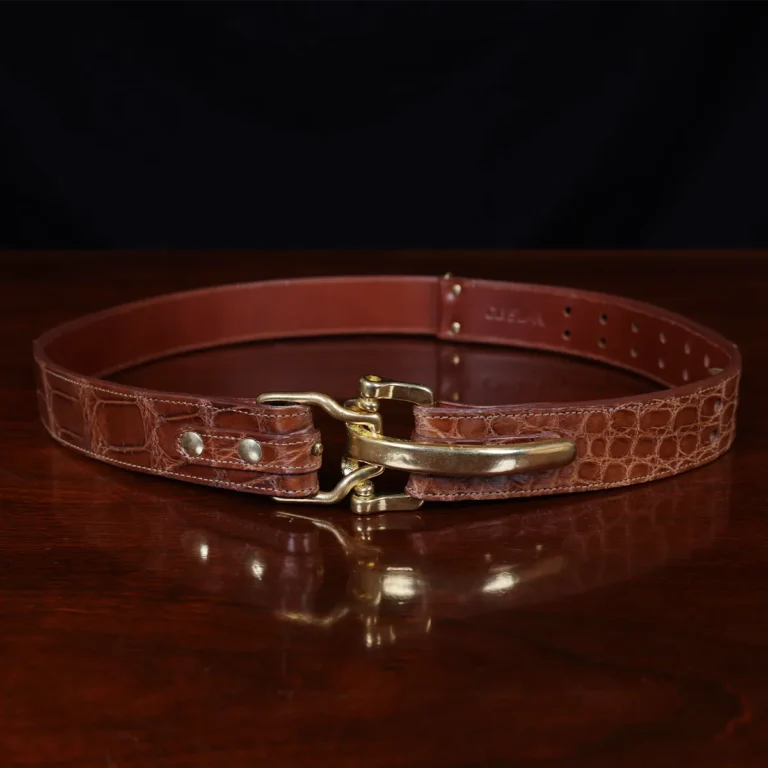 No. 5 Cinch Belt in brown American Alligator and brass buckle - ID 001 - front view on black background and wooden table