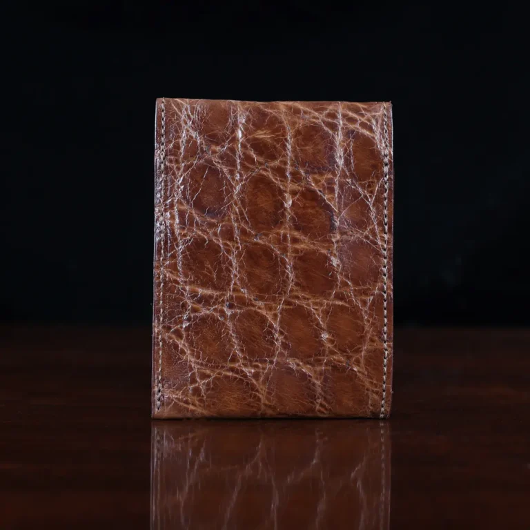 Front pocket wallet with flap in brown American Alligator - back view - 002 - on wood table with a dark background