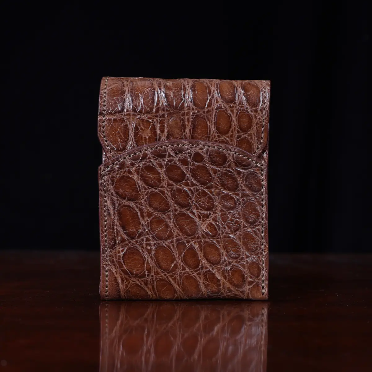Front pocket wallet with flap in brown American Alligator - front view - 002 - on wood table with a dark background