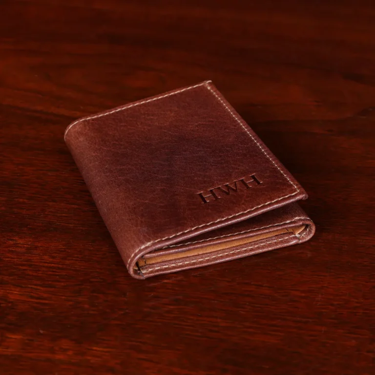 no 1 trifold wallet in brown steerhide on a wooden table - side view
